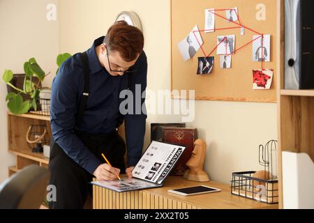 Männlicher Detective mit Ordner, der im Büro arbeitet Stockfoto