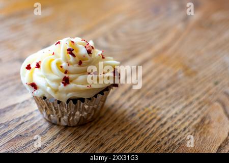 Ein Cupcake aus rotem Samt auf einem Holztisch mit Kopierraum. Stockfoto