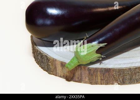 Zwei reife Auberginen auf einem Holzständer, auf hellem Hintergrund Stockfoto