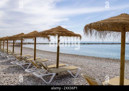 Foto vom wunderschönen Strand in Altea, Alicante in Spanien, mit Sonnenliegen und Strohschirmen am Kiesstrand Playa La Roda Stockfoto