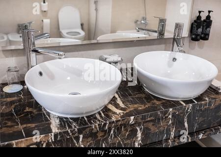 Badezimmer moderner Kosmetikbereich mit zwei runden Keramikwaschbecken. Ein moderner Kosmetikbereich im Bad mit zwei ovalen Waschbecken und einem Spiegel. Minimalistisches Bad Stockfoto