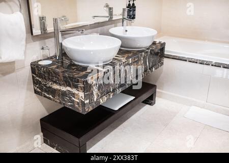 Badezimmer moderner Kosmetikbereich mit zwei runden Keramikwaschbecken. Ein moderner Kosmetikbereich im Bad mit zwei ovalen Waschbecken und einem Spiegel. Minimalistisches Bad Stockfoto