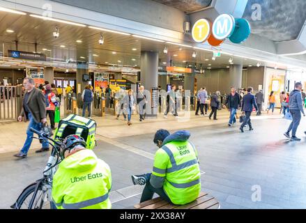 Die Fahrer von Uber Eats machen eine Mittagspause in Chatswood Sydney mit Elektro-E-Bike neben ihnen, in hiviz gelben Jacken, Chatswood, Sydney Stockfoto