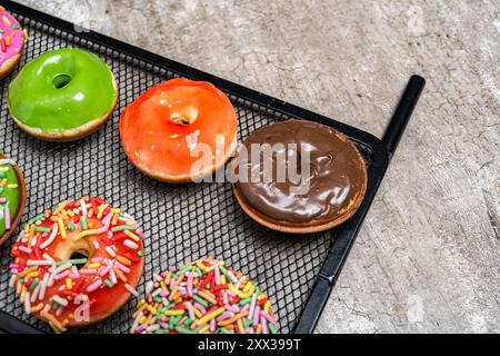Ein Tablett mit verschiedenen Mini-Donuts mit einer Schokolade in der Mitte. Die Mini-Donuts sind bunt und mit Streuseln bestreut Stockfoto