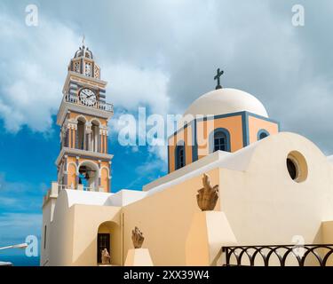 Santorin, Griechenland - 8. Oktober 2019: Berühmte Kirche mit blauer Kuppel und Glockenturm vor einem teilweise bewölkten Himmel. Stockfoto