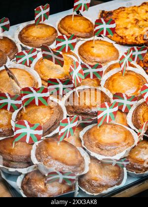 Präsentation von frisch gebackenem Gebäck, traditionell aus dem Baskenland, jedes mit kleiner ikurriña-Flagge gekrönt, in einer Bäckerei. Stockfoto