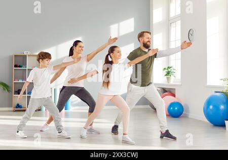 Glücklicher, aktiver Ehemann, Frau und ihre beiden Kinder, die zusammen einen Familienyoga machen. Stockfoto