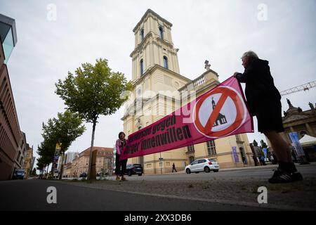 22. August 2024, Brandenburg, Potsdam: Teilnehmer an einem Protest der Bürgerinitiative für eine Potsdam ohne Garnisonkirche halten anlässlich der Eröffnung des Turms der Garnisonkirche ein Protestbanner mit der Aufschrift „Nazi-Kirche gegen den Willen der Bürger“. Der wiederaufgebaute Turm der umstrittenen Garrison Church wird mit einer Zeremonie wieder eröffnet. Die Bürgerinitiative sieht die Kirche als "Wahrzeichen des Terrors". Im März 1933 schüttelte Reichspräsident Paul von Hindenburg am „Tag der Töpfe“ vor der Kirche den neuen Reichskanzler Adolf Hitler die Hand Stockfoto