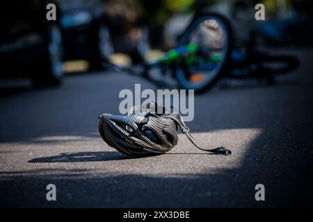 Berlin, Deutschland. August 2024. Symbolfoto zum Thema Fahrradunfälle (inszenierte Szene). Ein kaputter Fahrradhelm liegt neben einem Fahrrad auf einer Straße. Berlin, 21. August 2024. Quelle: dpa/Alamy Live News Stockfoto