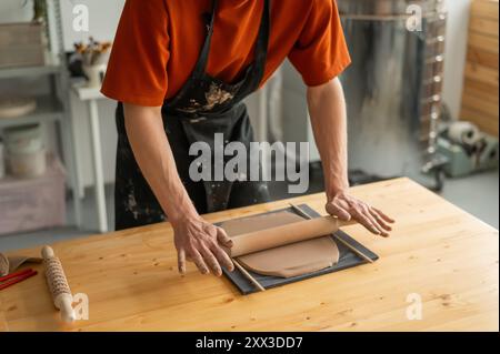 Nahaufnahme von Töpferhänden, die Ton ausrollen. Stockfoto