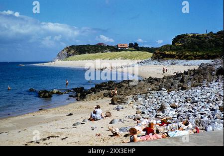 Menschen, die sich am Priory Bay Beach, Caldey Island, Pembrokeshire Wales, Großbritannien, Ende der 1950er Jahre sonnen Stockfoto