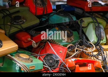 Ein Haufen alter farbenfroher Telefone mit Kabeln Stockfoto