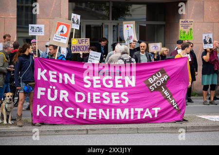 22. August 2024, Brandenburg, Potsdam: Teilnehmer eines Protestes der Bürgerinitiative für eine Potsdam ohne Garnisonkirche halten bei der Eröffnung des Garnisonskirchenturms ein Protestbanner mit der Aufschrift „kein Segen für diese Nachahmung“. Der wiederaufgebaute Turm der umstrittenen Garrison Church wird mit einer Zeremonie wieder eröffnet. Die Bürgerinitiative sieht die Kirche als "Symbol des Terrors". Im März 1933 schüttelte Reichspräsident Paul von Hindenburg am Potsdamer Tag vor der Kirche den neuen Reichskanzler Adolf Hitler die Hand. Foto: Christoph Soeder/ Stockfoto