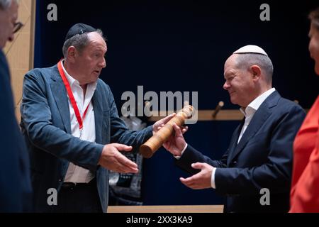 Potsdam, Deutschland. August 2024. Bundeskanzler Olaf Scholz (SPD, r) erhält von Alexander Kogan während eines Besuchs im Potsdamer Synagogenzentrum eine Esther-Schriftrolle für die Gemeinde. Scholz ist auf einer Sommerreise in seinen Wahlkreis. Quelle: Sebastian Christoph Gollnow/dpa/Alamy Live News Stockfoto