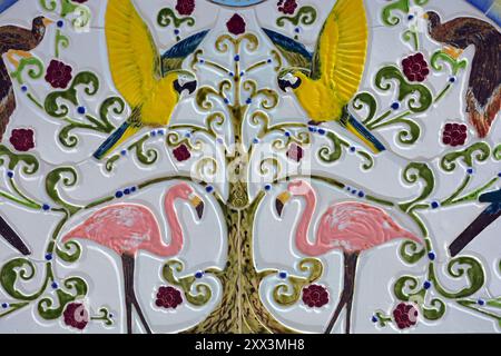 Architektur, Baumaterialien, Gemälde an den Wänden. Helle Zeichnungen von farbigen Papageien, rosa Flamingos aus Porzellan und Fayence-Platten, mosa Stockfoto