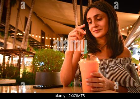 Nahaufnahme junge hübsche kaukasische Frau sitzen drinnen im asiatischen Café trinken Sie gesunden rosa thai Smoothie in südostasien, Bangkok, Thailand. Asiatique Popu Stockfoto