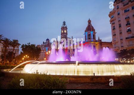 Ein wunderschön beleuchtetes Gebäude in der Abenddämmerung, mit bunten Lichtern und einem herrlichen Brunnen vorne Stockfoto