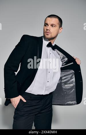 Ein Mann in einem schwarzen Anzug passt seine Jacke an und zeigt das Futter. Stockfoto