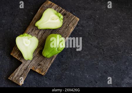 Frischer grüner stacheliger Kürbis, Chayote auf hölzernem Hintergrund, (Sechium edulis) Stockfoto