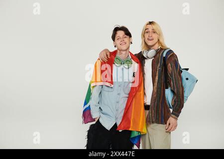 Zwei junge Menschen stehen zusammen, lächelnd und mit einer Stolzfahne auf weißem Hintergrund. Stockfoto