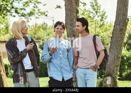 Drei queere Freunde laufen in einem Park. Sie sind alle lässig gekleidet und scheinen ein Gespräch zu führen. Stockfoto