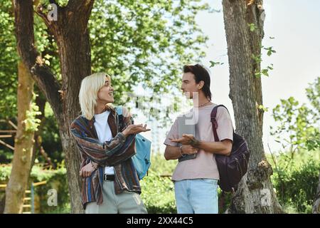 Zwei junge Freunde unterhalten sich zwanglos in einem sonnigen Park, umgeben von Bäumen. Stockfoto