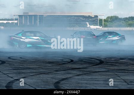 British Motor Show 2024, in Farnborough, Hampshire, England, Vereinigtes Königreich vom 15. bis 18. August 2024. Tag 2 der jährlichen Veranstaltung im Farnborough International Exhibition Centre. Drei Autos in der Arena, die eine Driftausstellung durchführen. Stockfoto