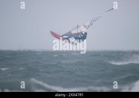 Beachlands, Hayling Island. August 2024. Starke Winde und zeitweilige Regenfälle für die Südküste heute, als Ex-Hurrikan Ernesto an Land kam. Windsurfer genießen die anspruchsvollen Bedingungen auf Beachlands, Hayling Island in Hampshire. Quelle: james jagger/Alamy Live News Stockfoto