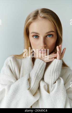 Blonde Frau in weißer Strickjacke schaut in die Kamera. Stockfoto