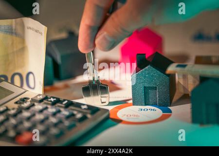 Preise für die Finanzierung von Wohnungsinvestitionen. Schlüssel zur neuen Haustür mit der Hand halten. Berechnungen von Haushaltsausgaben Hintergrund Immobilien. Stockfoto