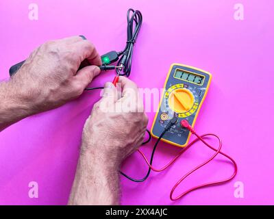 Adapterspannung mit einem Multimeter prüfen. Im Hintergrund Stockfoto