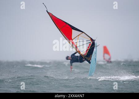 Beachlands, Hayling Island. August 2024. Starke Winde und zeitweilige Regenfälle für die Südküste heute, als Ex-Hurrikan Ernesto an Land kam. Windsurfer genießen die anspruchsvollen Bedingungen auf Beachlands, Hayling Island in Hampshire. Quelle: james jagger/Alamy Live News Stockfoto