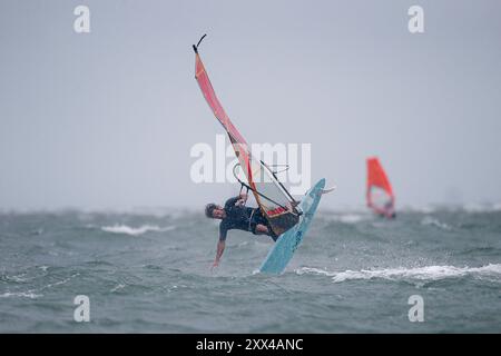 Beachlands, Hayling Island. August 2024. Starke Winde und zeitweilige Regenfälle für die Südküste heute, als Ex-Hurrikan Ernesto an Land kam. Windsurfer genießen die anspruchsvollen Bedingungen auf Beachlands, Hayling Island in Hampshire. Quelle: james jagger/Alamy Live News Stockfoto