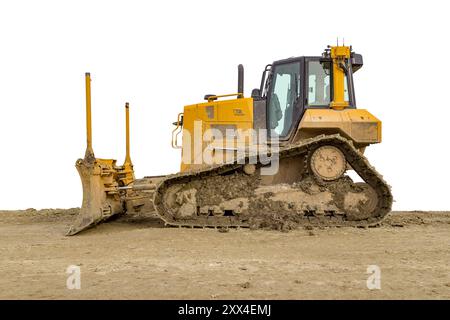 Gelber Bulldozer auf einer lehmigen Baustelle, teilweise isoliert mit weißem Rücken Stockfoto