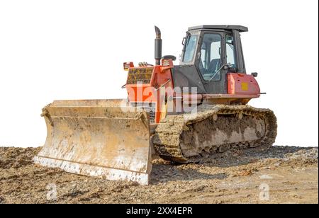 Roter schmutziger Bulldozer auf einer lehmigen Baustelle, teilweise isoliert in weißer Rückseite Stockfoto