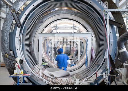 22. August 2024, Sachsen, Döbeln: Ein Mitarbeiter der Partzsch-Gruppe arbeitet an einem Windkraftstator für Windräder in einer Produktionshalle. Das Unternehmen feiert sein 70-jähriges Bestehen am 22. August 2024. Foto: Sebastian Kahnert/dpa Stockfoto