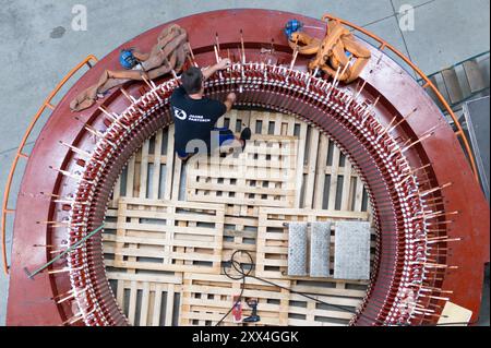 22. August 2024, Sachsen, Döbeln: Ein Mitarbeiter der Partzsch-Gruppe arbeitet an einem Windkraftstator für Windräder in einer Produktionshalle (Foto mit Drohne). Das Unternehmen feiert sein 70-jähriges Bestehen am 22. August 2024. Foto: Sebastian Kahnert/dpa Stockfoto