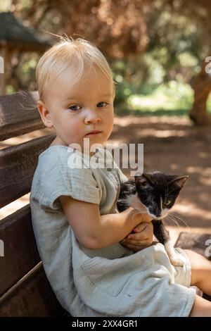 Niedliches Mädchen, das mit Kätzchen im öffentlichen Park spielt Stockfoto