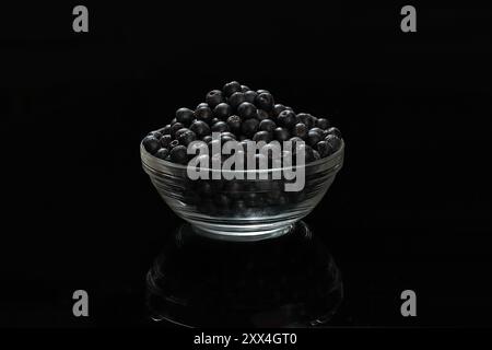 Frisch gepflückte Arschbeeren in einer Glasschale auf schwarzem Hintergrund Stockfoto