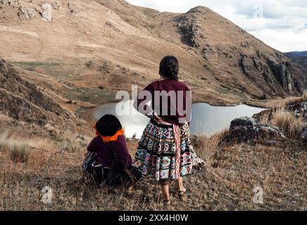 Zwei Quechua-Frauen in traditioneller Kleidung, die auf einen See in den Anden im Heiligen Tal, Peru, blicken Stockfoto