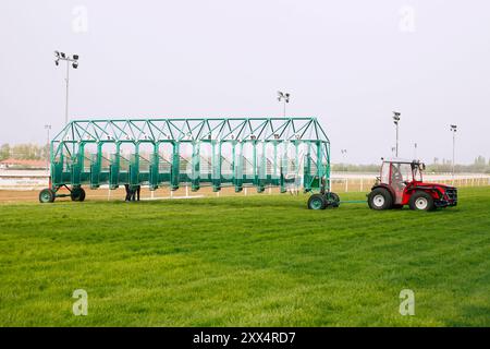 Leere Pferderennen, die auf Reiter warten. Grün gefärbtes Startfeld beim Start mit der Traktormaschine am hippodrom des Pferdes. E Stockfoto