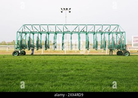 Leere Pferderennen, die auf Reiter warten. Grün gefärbtes Startfeld beim Start mit der Traktormaschine am hippodrom des Pferdes. E Stockfoto