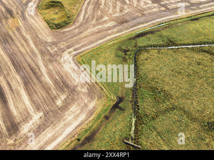 Luftaufnahme eines Entwässerungsgrabens durch ein Feld oder Weide in Mitteljütland, Dänemark Stockfoto