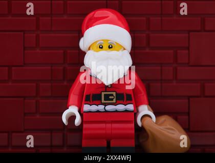Tambow, Russische Föderation - 21. August 2024 Porträt der Minifigur Lego Santa Claus mit seiner Tasche vor rotem Backsteinmauerhintergrund. Stockfoto