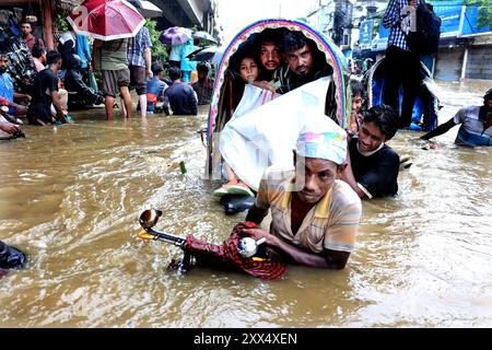 Chittagong, Muradpur, Bangladesch. August 2024. Ein Rikscha-Fahrer zieht Kunden durch tiefes Wasser, das die Straßen von Muradpur in der Stadt Chittagong überschwemmt, nach anhaltendem Regen. 157 mm Niederschlag in Chittagong hat in verschiedenen Teilen der Stadt Wasserabfälle verursacht. Einige Straßen sind für den Verkehr gesperrt. (Kreditbild: © Mohammed Shajahan/ZUMA Press Wire) NUR REDAKTIONELLE VERWENDUNG! Nicht für kommerzielle ZWECKE! Stockfoto