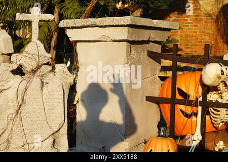 Schatten eines Spooky man zwischen Jack-O'-Laterne Halloween Kürbisse, Skelett und Tombstone Stockfoto