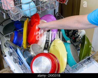 Horizontal der Hand einer Frau, die Geschirr in einen Geschirrspüler stellt. Stockfoto