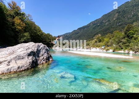 Junge, Touristen, die von einem großen Felsen in einen spektakulären soca-Fluss springen, Urlaub an einem heißen Sommertag genießen, um im kalten Alpenfluss in slowenien zu schwimmen Stockfoto