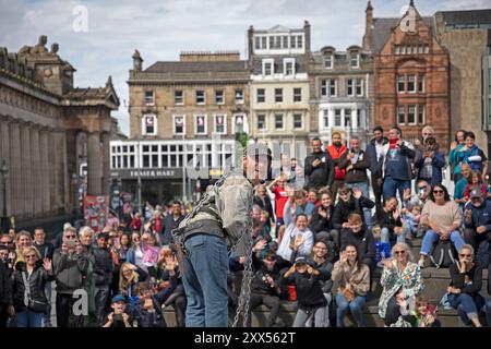 Dinburgh Festival Fringe, Schottland, Großbritannien. August 2024. Letzter Donnerstag für die Edfringe Street Artists, weniger Leute in der Nähe, aber immer noch ein vernünftiges Publikum für die erfahrenen Künstler in Royal Mile und The Mound. Im Bild: Todd unterhält auf dem Mound Pitch mit seiner Straight Jacke und Ketten. Quelle: Arch White/Alamy Live News. Stockfoto