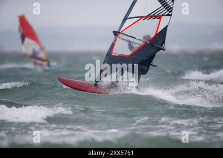 Beachlands, Hayling Island. August 2024. Starke Winde und zeitweilige Regenfälle für die Südküste heute, als Ex-Hurrikan Ernesto an Land kam. Windsurfer genießen die anspruchsvollen Bedingungen auf Beachlands, Hayling Island in Hampshire. Quelle: james jagger/Alamy Live News Stockfoto